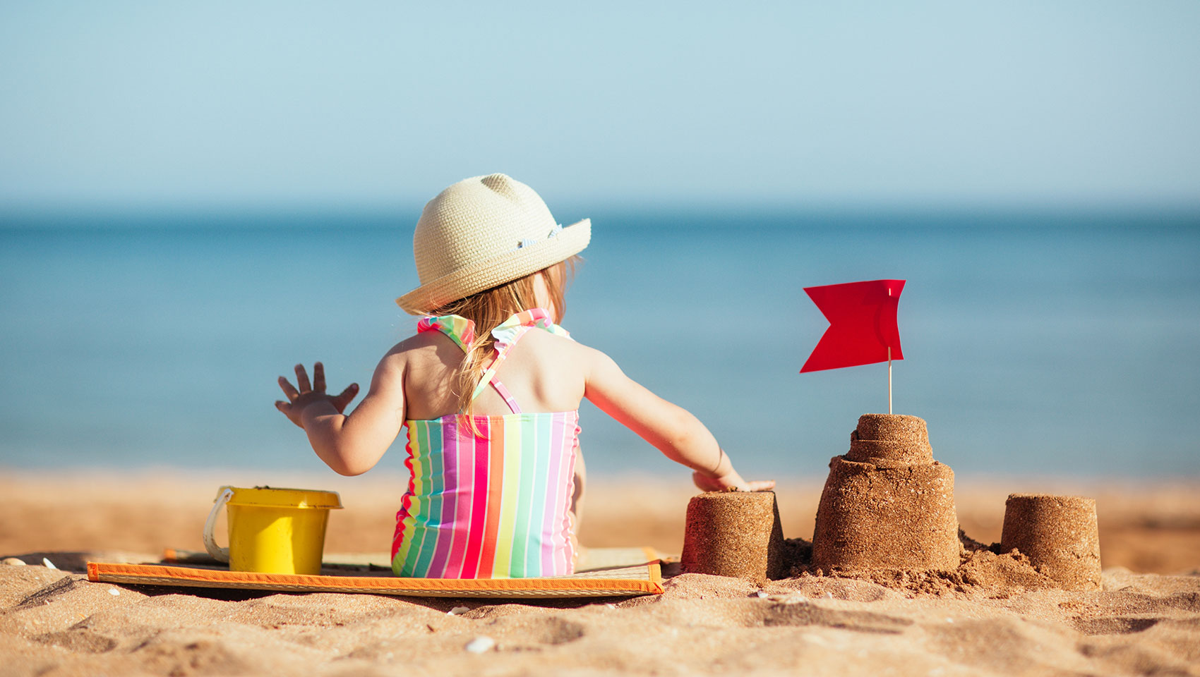 little girl playing in the sand at the beach